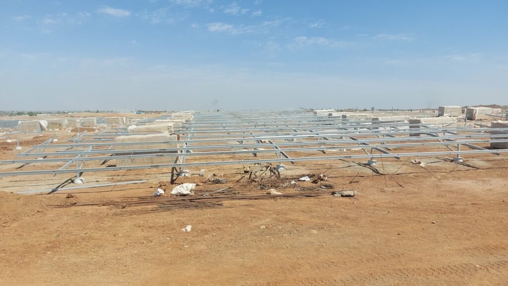 a group of metal structures in the middle of a dirt field