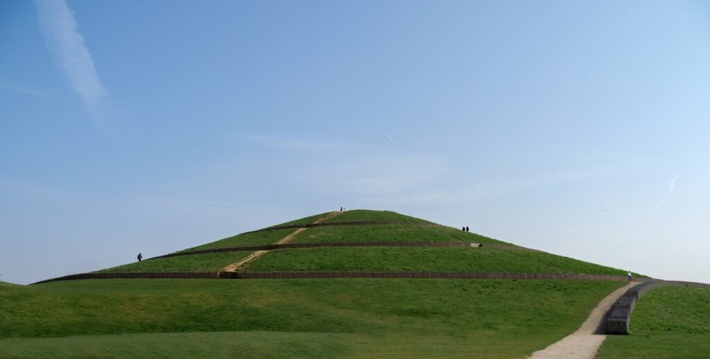 a grassy hill with a long path going up it