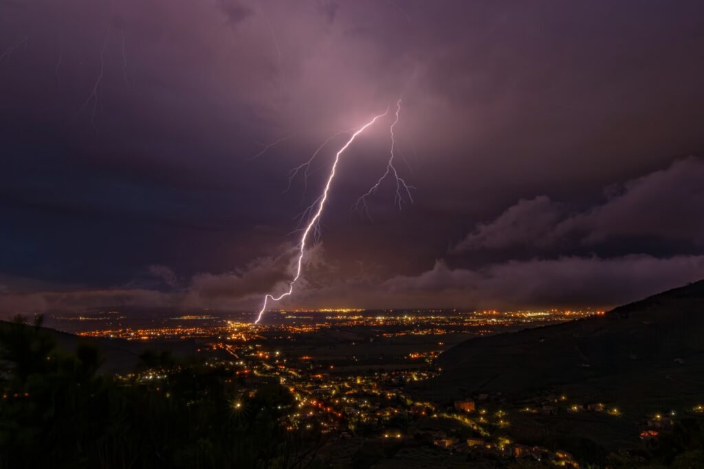 Lightning strikes illuminate a city at night.