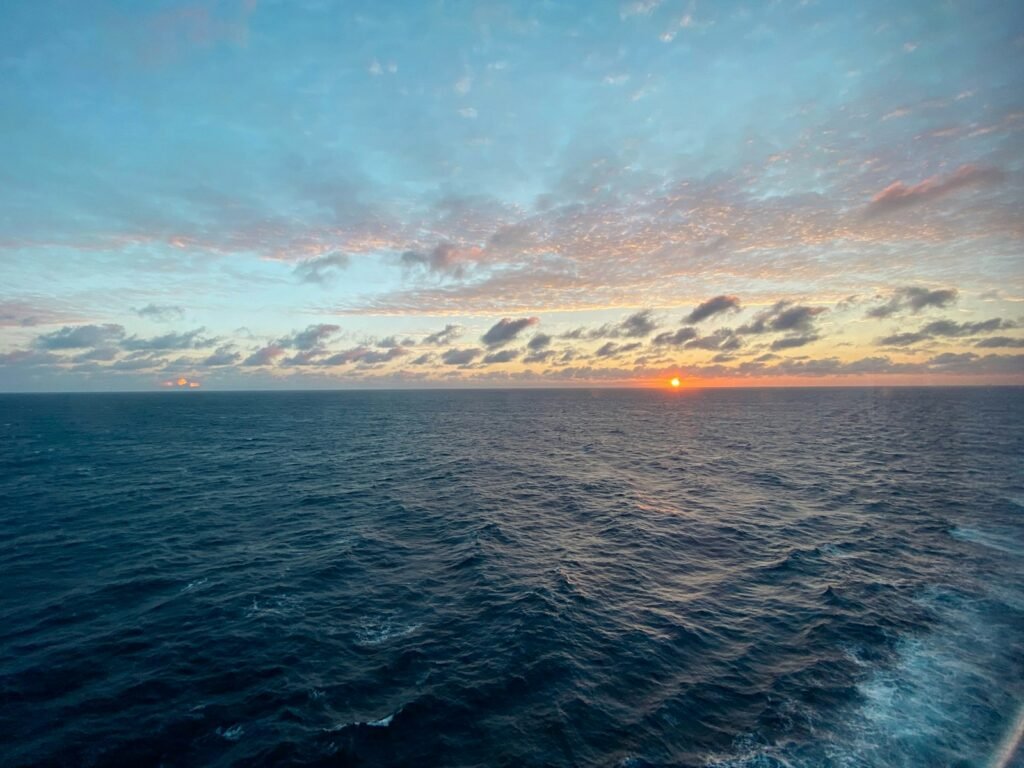 the sun is setting over the ocean as seen from a boat