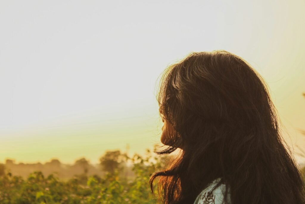 a woman with long hair standing in a field