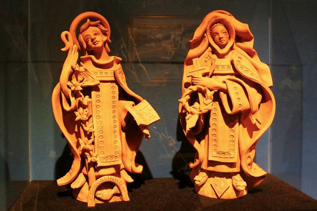Two terracotta figures of women in traditional attire.