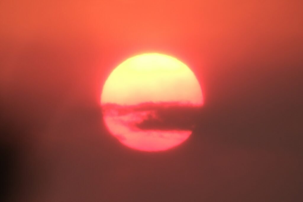 The sun is setting behind a hazy sky
