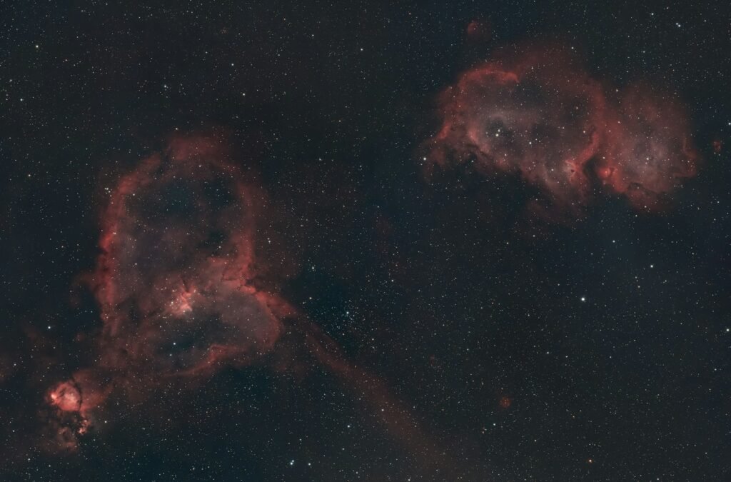 Two red nebulae in a star-filled sky