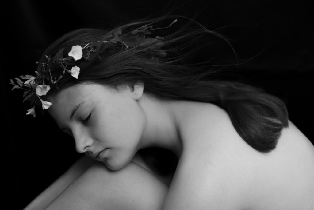 Young woman with flower crown, eyes closed, black background