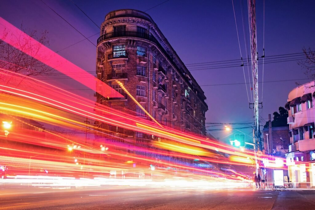 time-lapse photography of cars passing through the road between buildings during night time