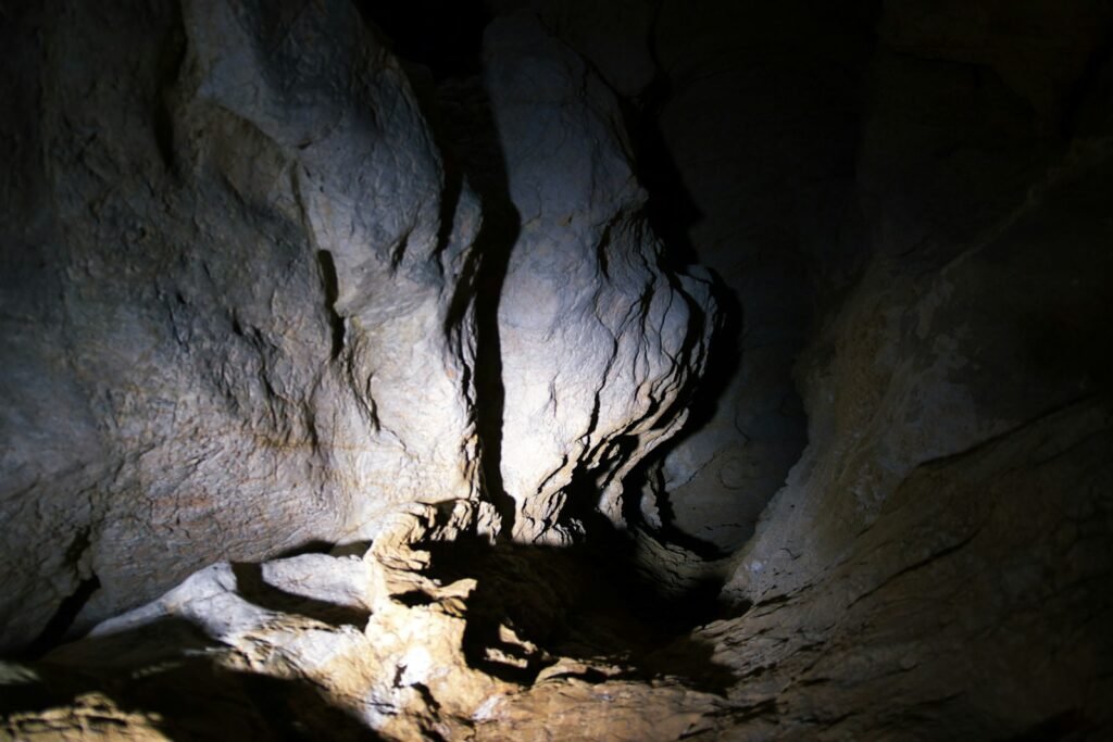 A dark cave with rock formations illuminated by light