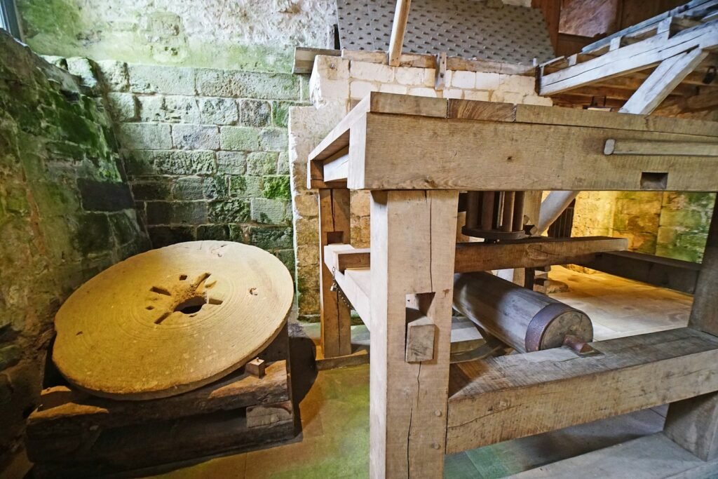 Old millstone and wooden machinery inside a stone building