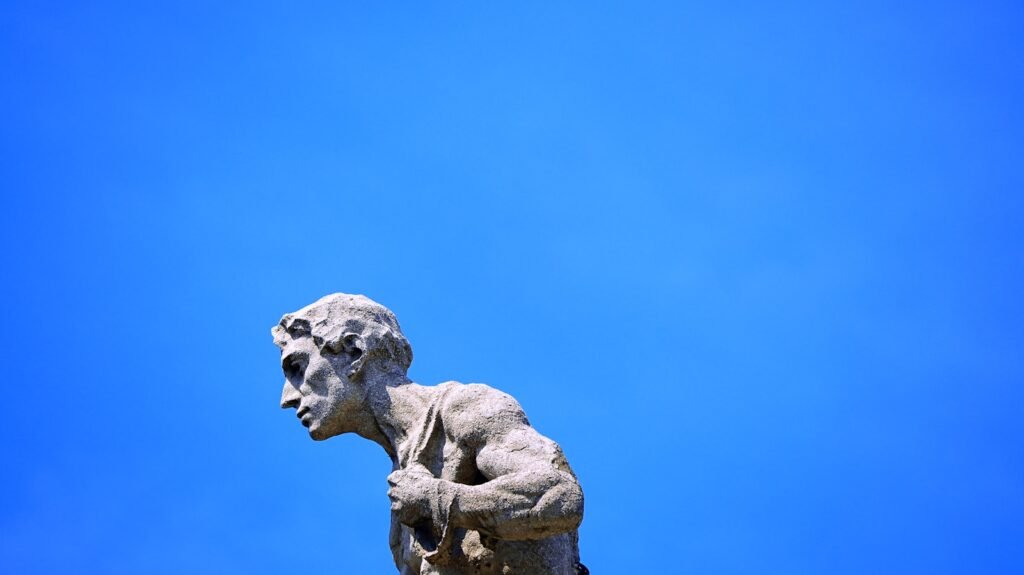 Stone statue of a man against a bright blue sky